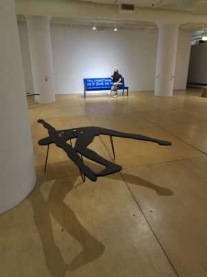 Crip installation view. Person sitting on a blue bench.