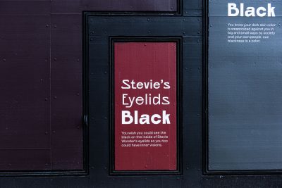 Exterior building painted in shades of black. In the center panel, painted red, it reads, 