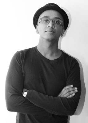 Black and white headshot of Dawit wearing a black shirt with glasses and a hat. Dawit's arms are folded and is wearing a watch on his left wrist.