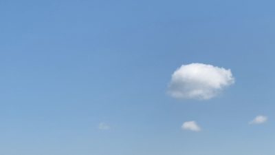 Image features a blue sky with a large white cloud in the center right with two smaller clouds, one directly below it and one to left of it.